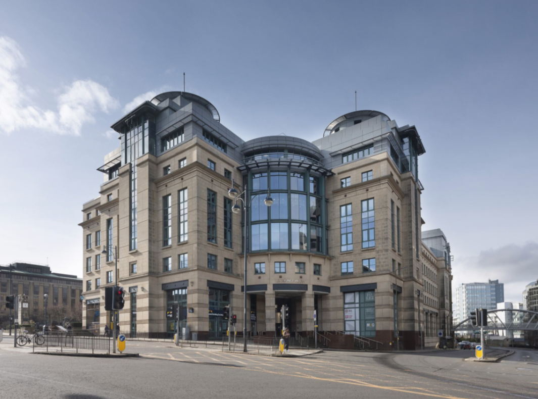 A large, modern building named Exchange Plaza boasts a curved glass facade and stone exterior. Its multiple floors and corner towers gracefully rise at an intersection with traffic lights and pedestrian crossings, all under a clear blue sky.