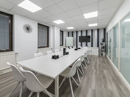 Spacious conference room on George Street featuring a long white table surrounded by white chairs. One wall has black and white stripes while large windows line the opposite side. Equipped with a wall clock, large TV screen, and cabinets, the room boasts a modern, minimalist design.