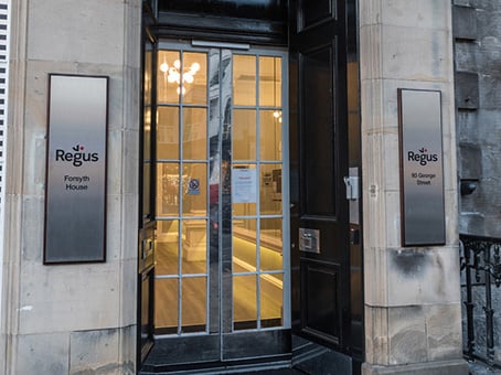 Entrance to a building with two signs displaying Regus—Forsyth House and 83 George Street. The glass door offers a glimpse of the illuminated interior. The stone facade is complemented by a dark wooden door frame, perfectly embodying the charm of George Street.