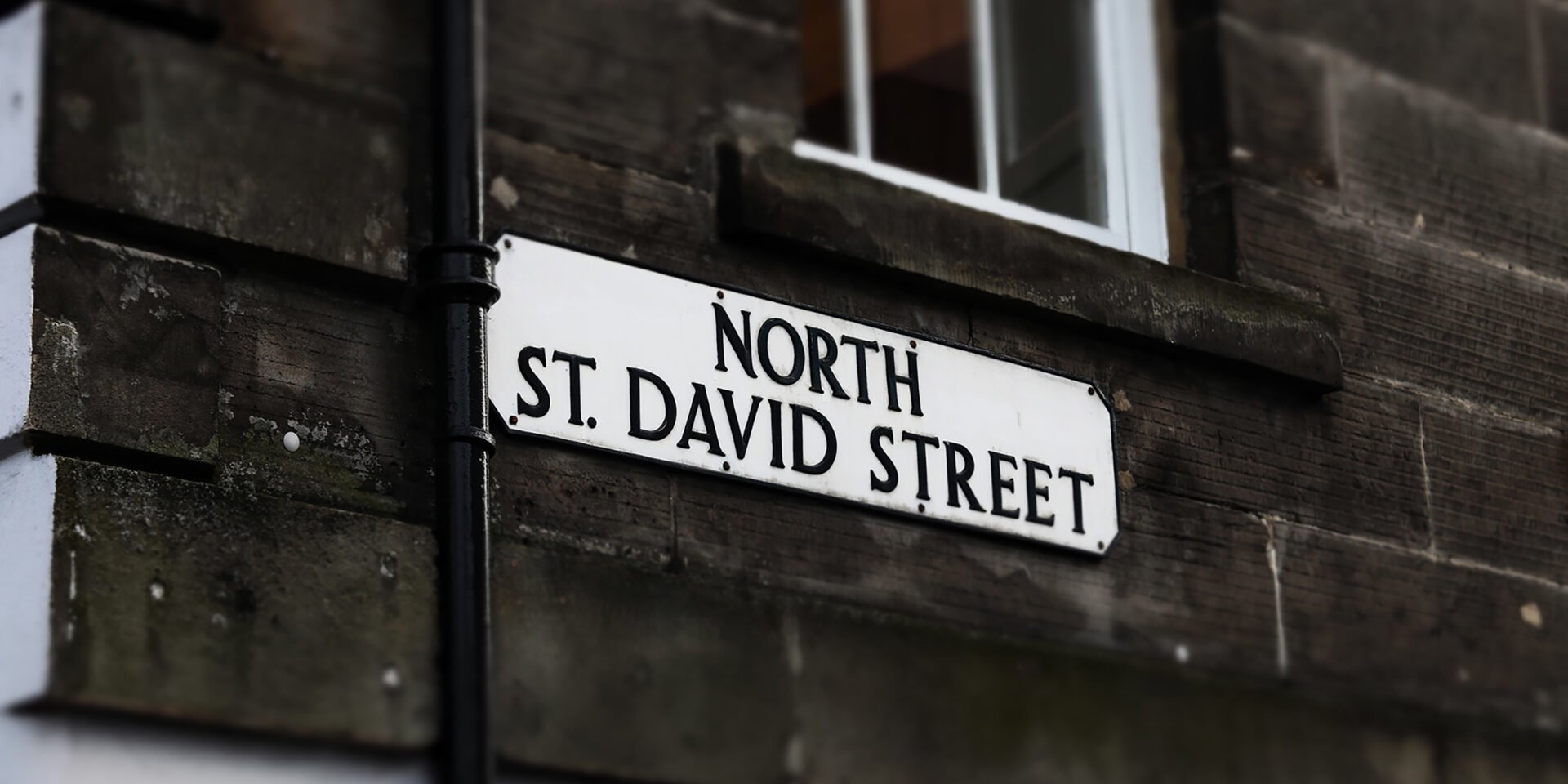 A street sign reading North St. David Street is mounted on a stone wall, typical of Edinburghs charming architecture, with a window above.